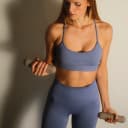 Vrouw voert bicep curls uit met beige Pilates dumbbells thumbnail